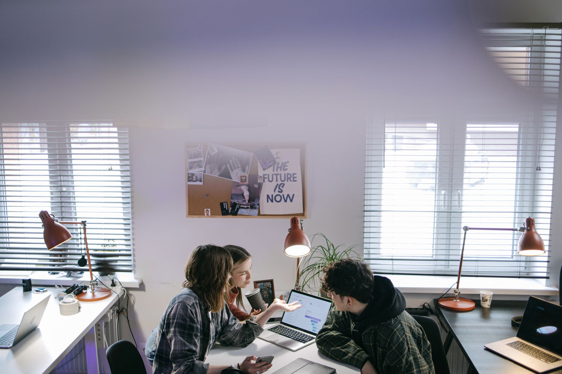 A group of people discussing ideas around laptops in a bright, modern office space — illustrating: Best Virtual NOC Groups for Small Businesses in Central Florida in 2026